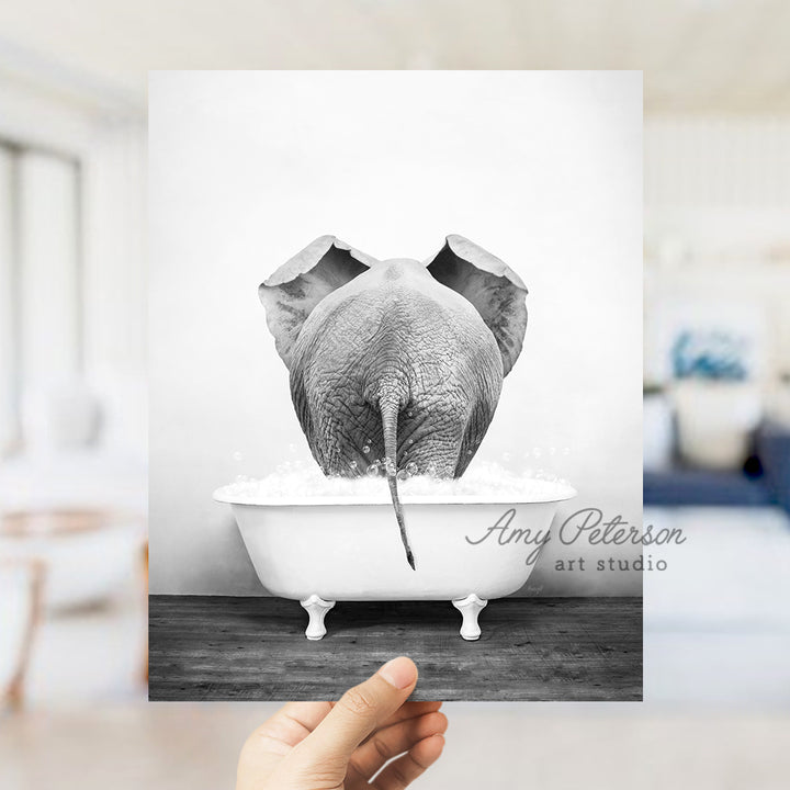 a hand holding up a black and white photo of an elephant in a bathtub