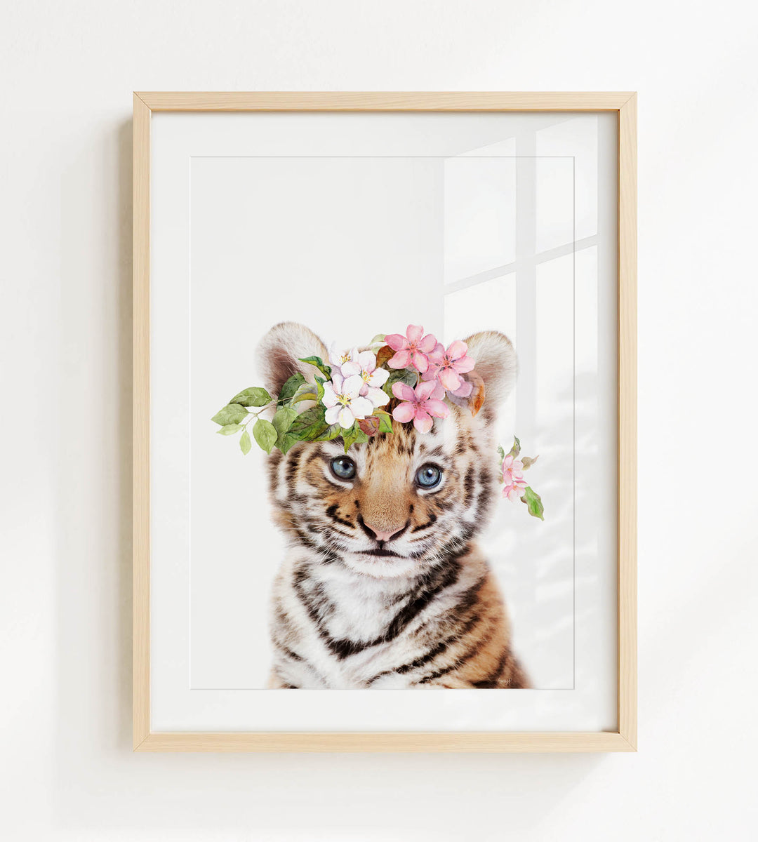 A young tiger cub wearing a floral headpiece, with its eyes looking directly at the camera.