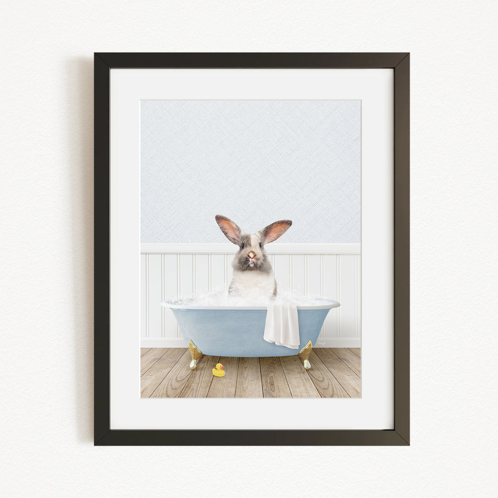 A white rabbit sitting in a blue bathtub filled with bubbles, with yellow rubber duckies floating around it.