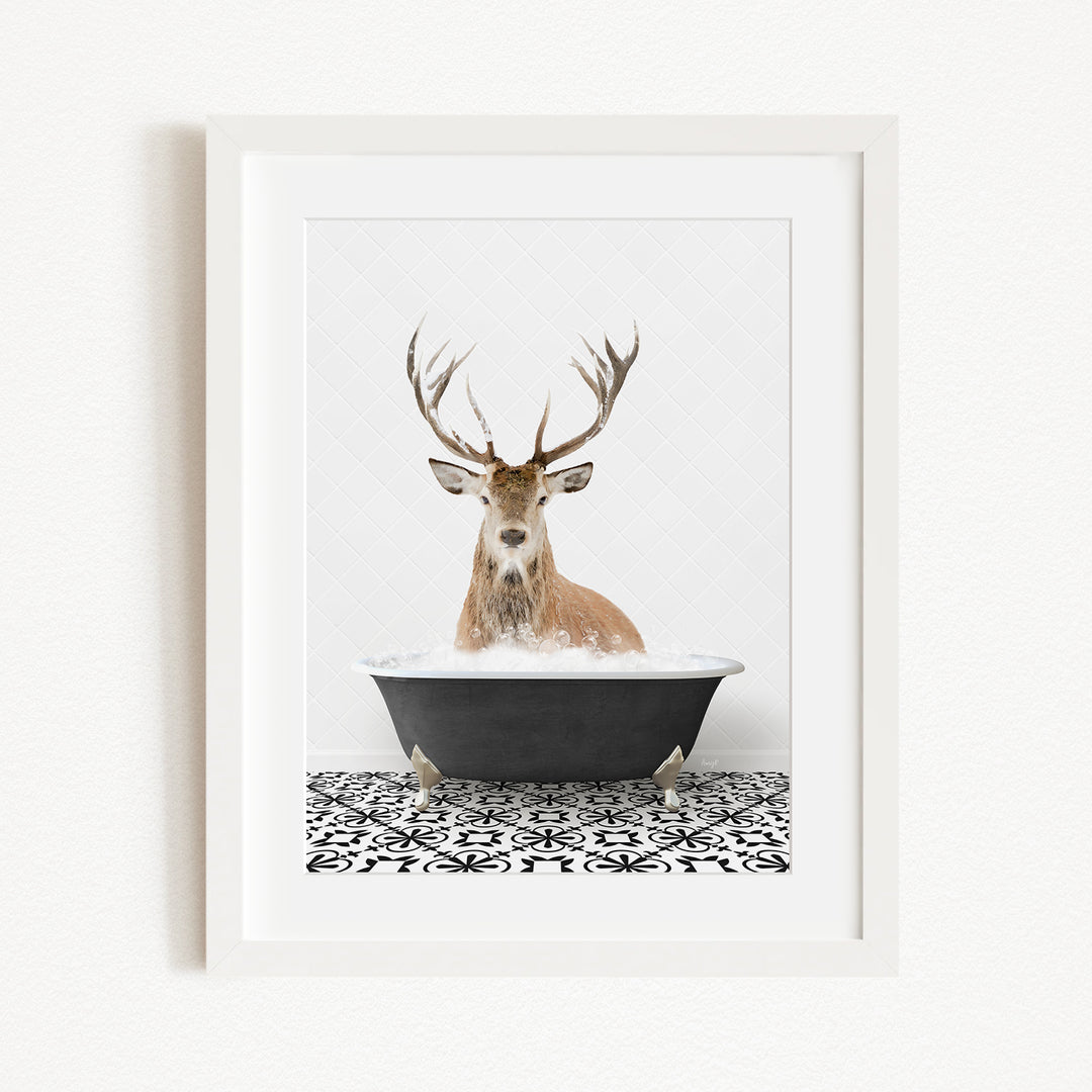 A deer with large antlers is sitting in a black bathtub filled with water, creating a whimsical and unexpected scene.
