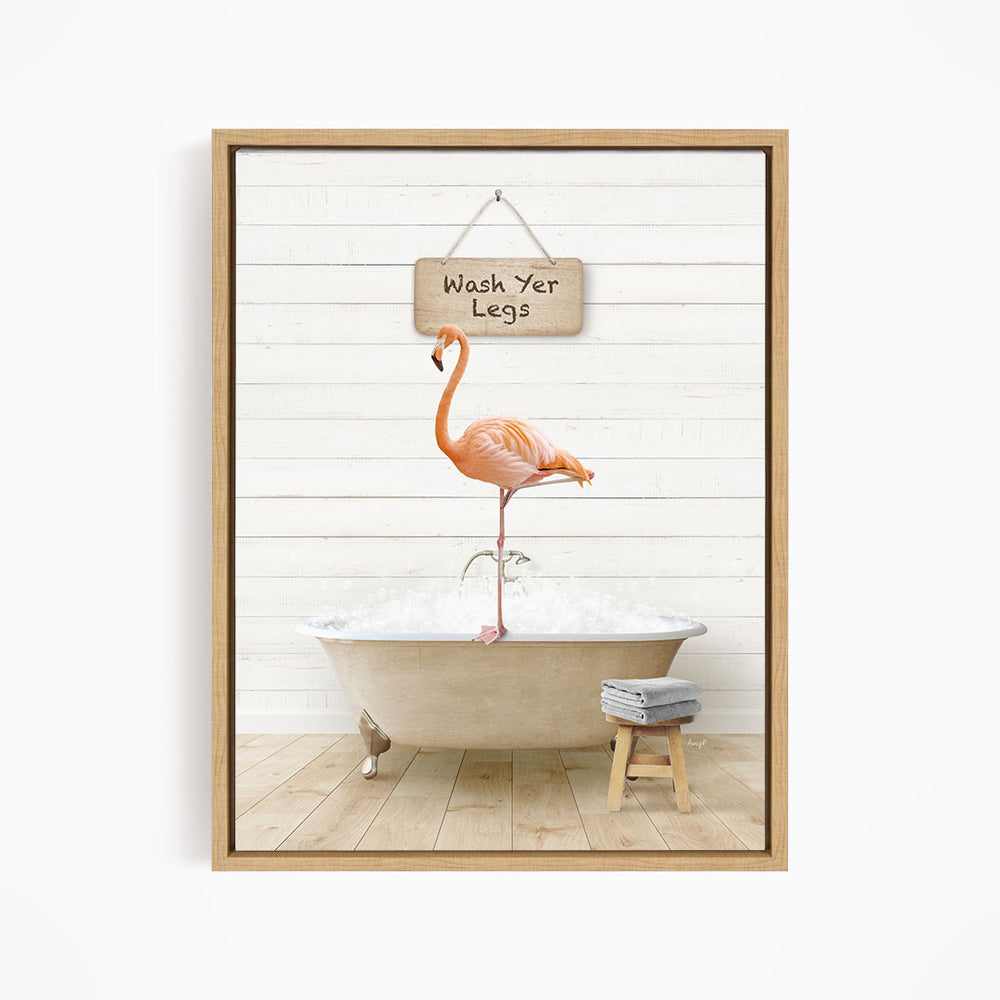 A framed image depicting a pink flamingo standing in a bathtub, with a sign above it that says "Wash Your Legs".