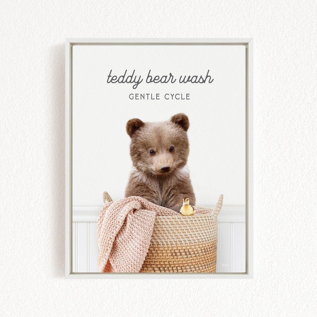 A teddy bear sitting in a woven basket, with a blanket and a toy duck nearby.