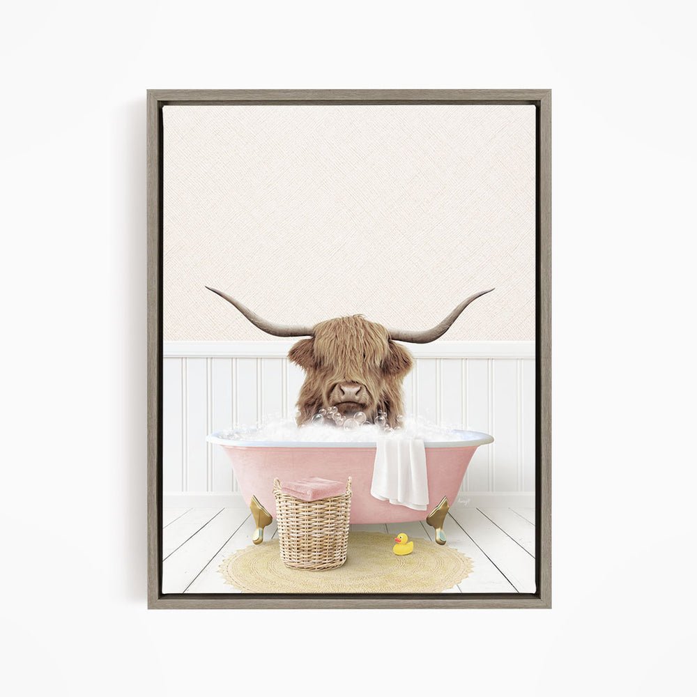 A brown cow with long horns is sitting in a pink bathtub filled with bubbles, surrounded by a yellow rubber duck and a wicker basket.