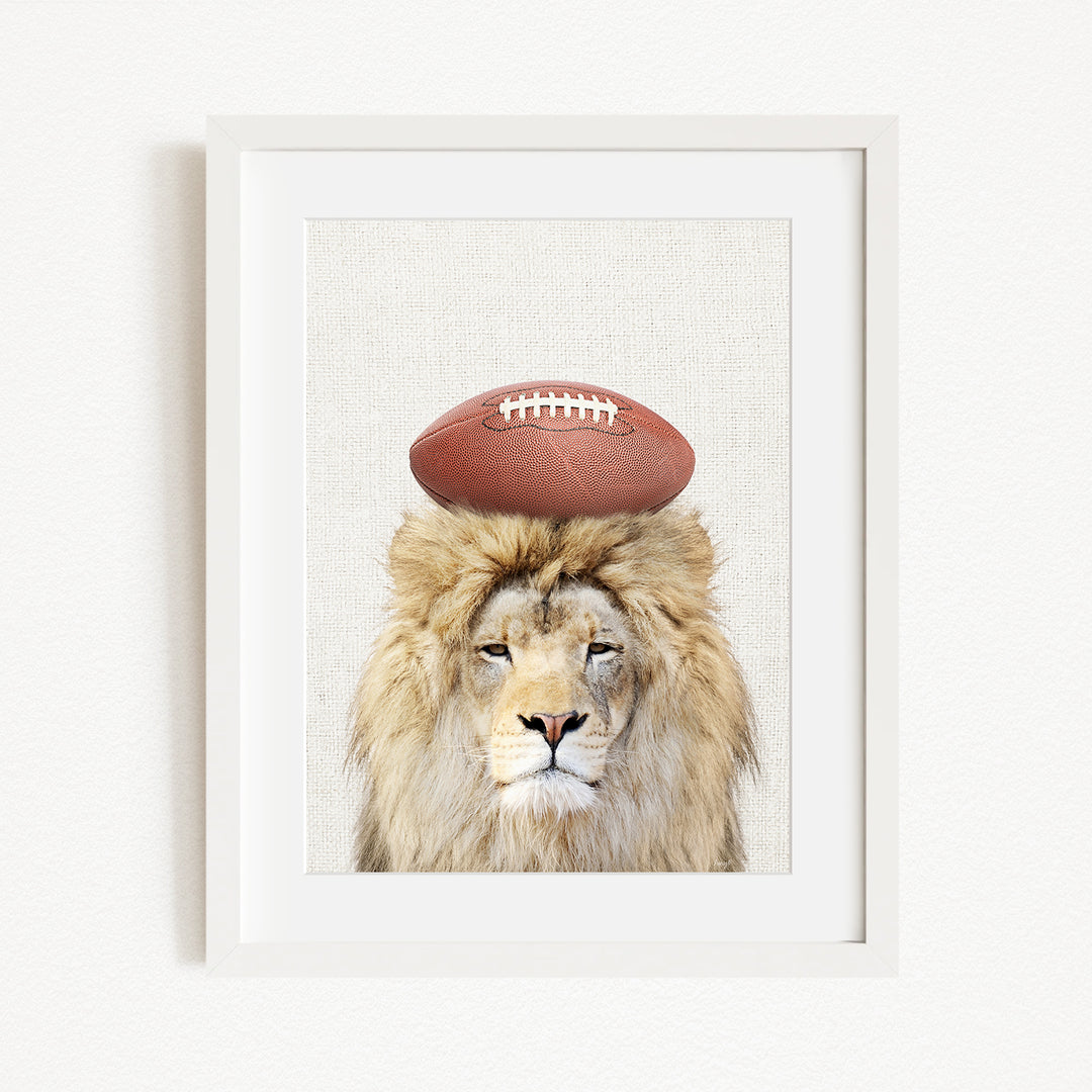 A framed image of a lion with a football on its head.