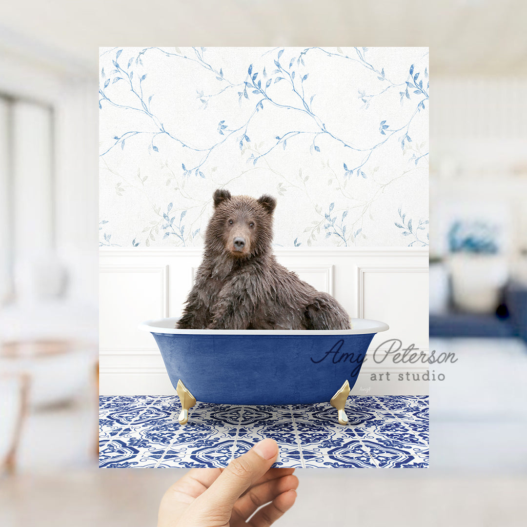 a hand holding a card with a bear in a bathtub