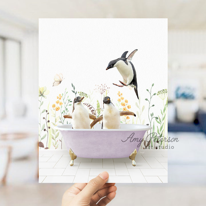 a hand holding a card with three penguins in a bathtub