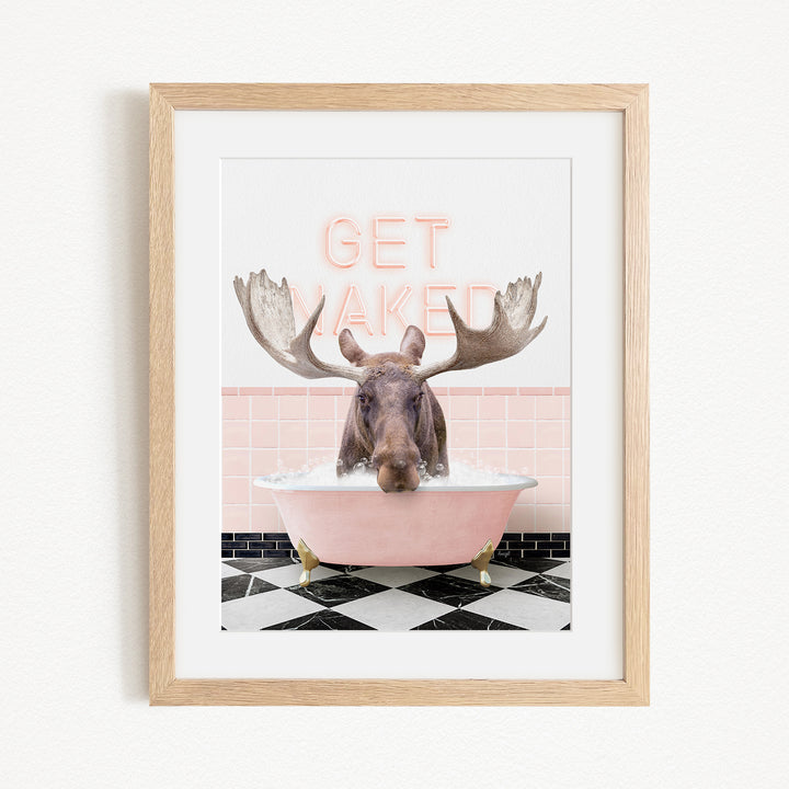 A framed image depicting a moose with large antlers sitting in a pink bathtub, with the text "GET NAKED" displayed above it.