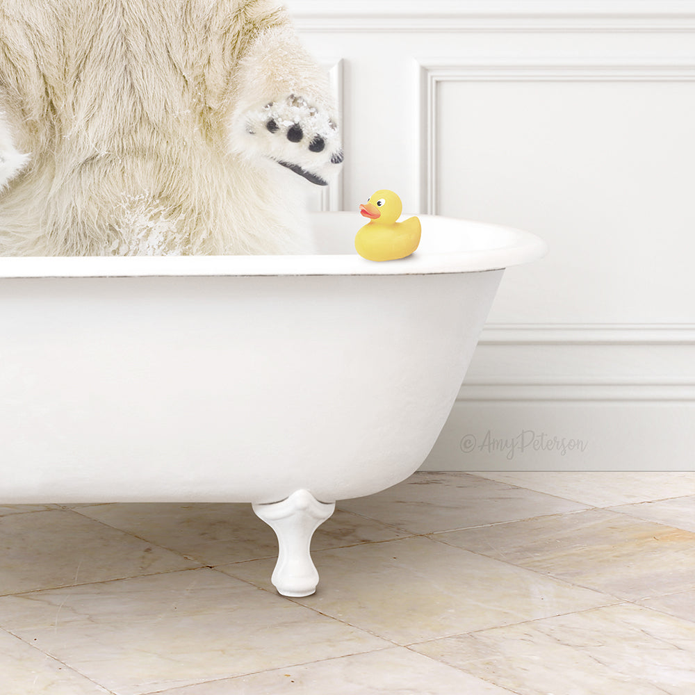 A polar bear is sitting in a white bathtub, with a yellow rubber duck placed on the edge of the tub.