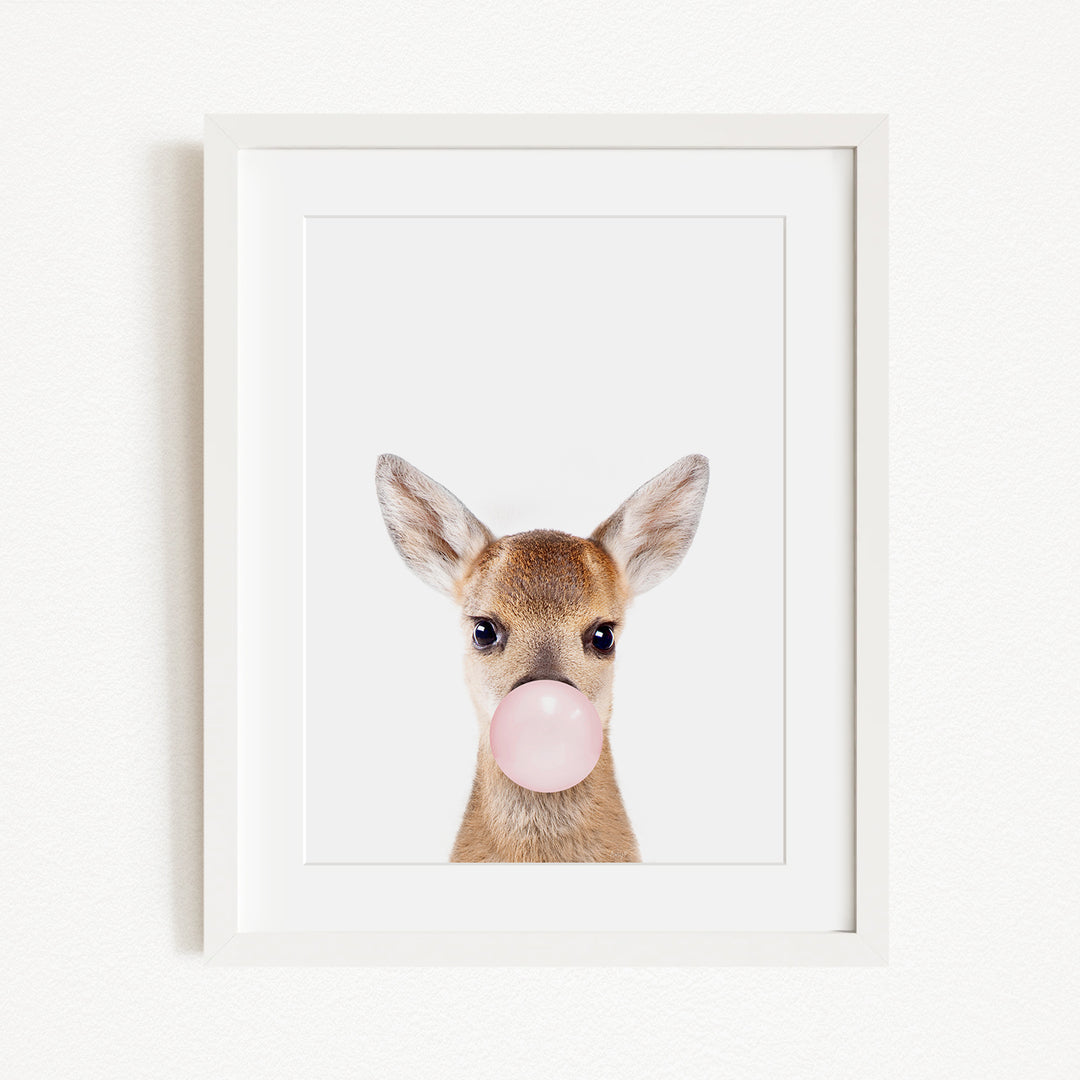 A framed image of a deer blowing a bubble with a pink bubble gum bubble.
