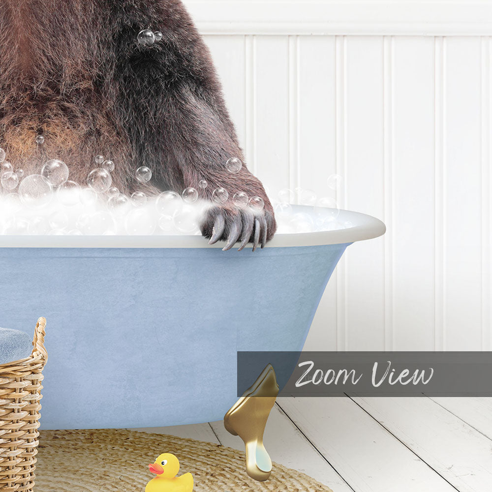 A close-up of a bear's paw in a blue bathtub filled with bubbles, with a rubber duck and a basket nearby.