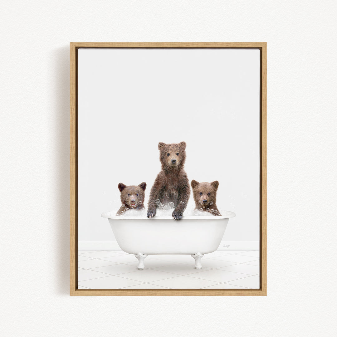 A framed image depicting three brown bears sitting in a white bathtub, with one bear standing and the other two sitting.