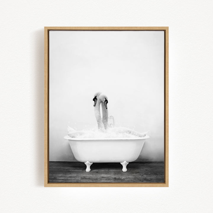 A black and white photograph of a swan standing in a bathtub filled with water, creating a whimsical and playful scene.