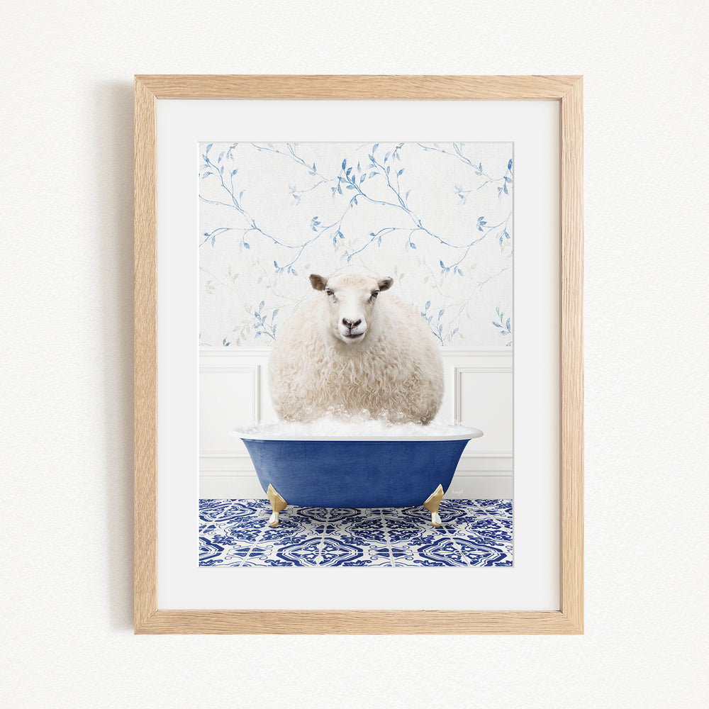 A fluffy white sheep sits in a blue bathtub, surrounded by a blue and white patterned tile floor.