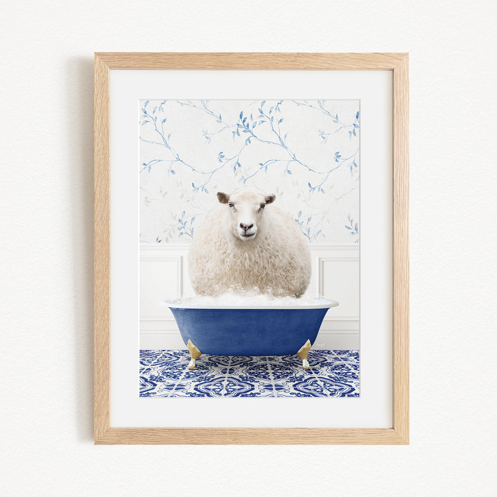 A fluffy white sheep sits in a blue bathtub, surrounded by a blue and white patterned tile floor.