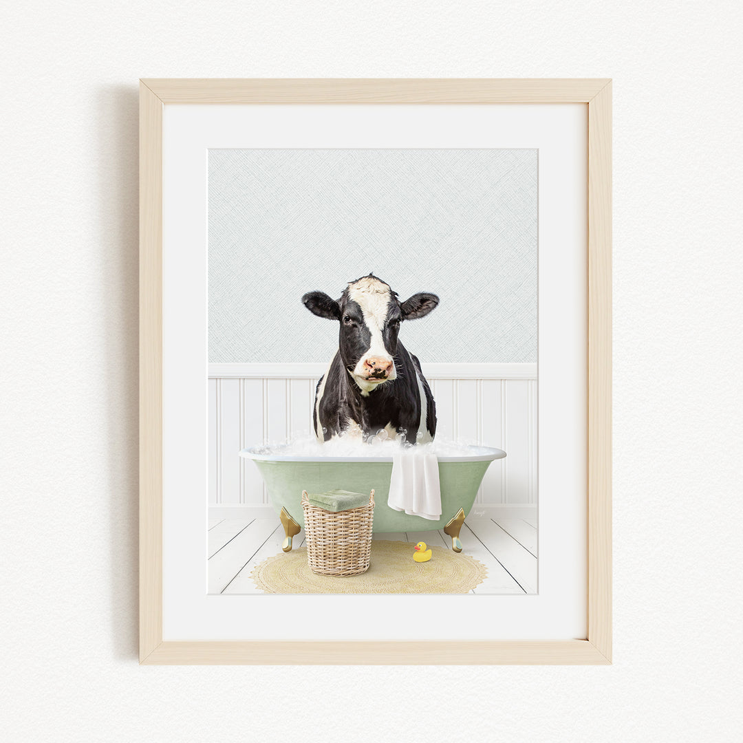 A black and white cow is sitting in a green bathtub filled with water, surrounded by rubber ducks and a basket.