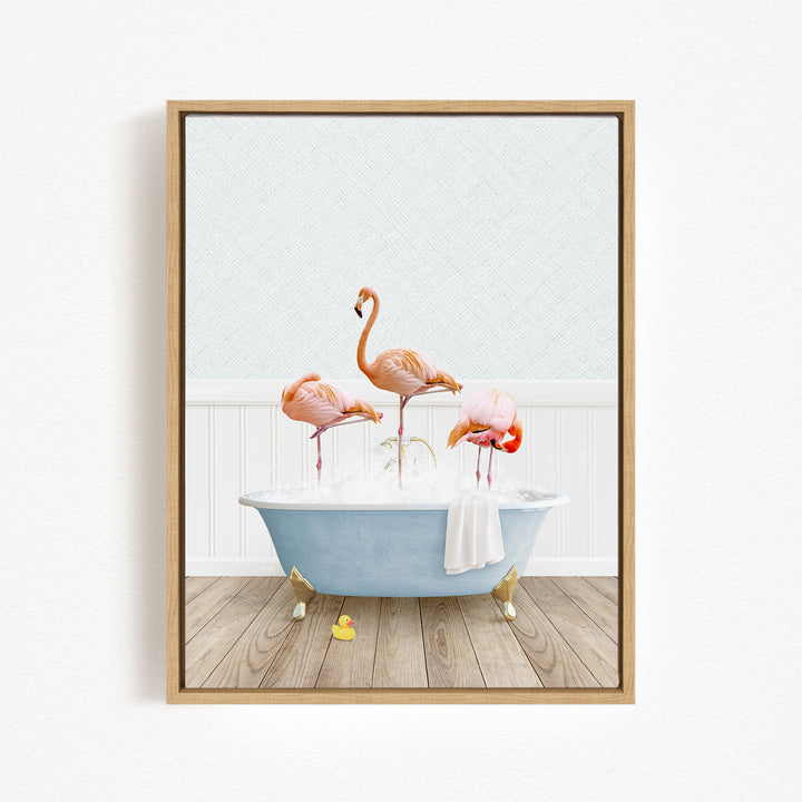 A framed image depicting three flamingos standing in a blue bathtub filled with bubbles, with a white towel hanging on the side.