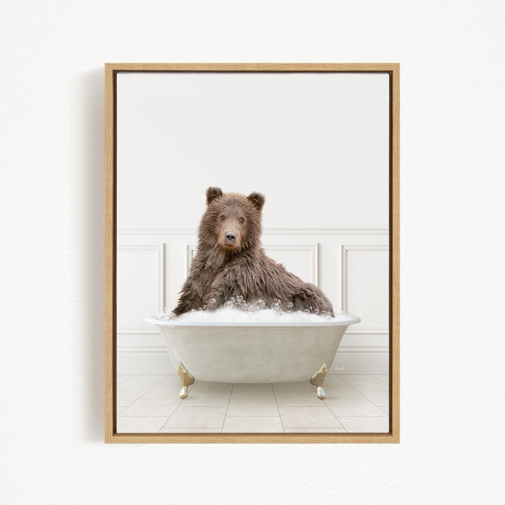 A brown bear sitting in a white bathtub filled with bubbles, looking directly at the camera.