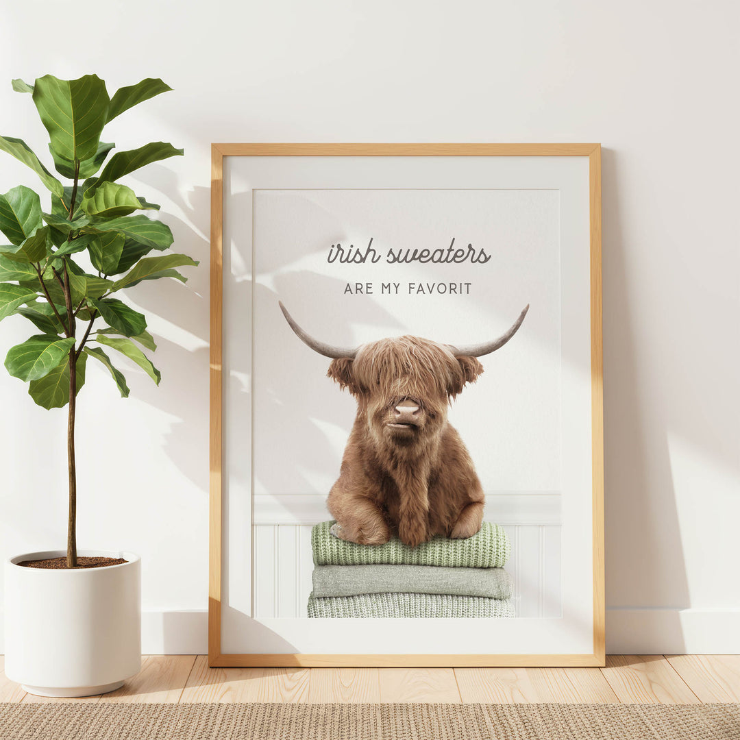 a framed poster of a brown Highland cow with large horns, sitting on a stack of green towels.