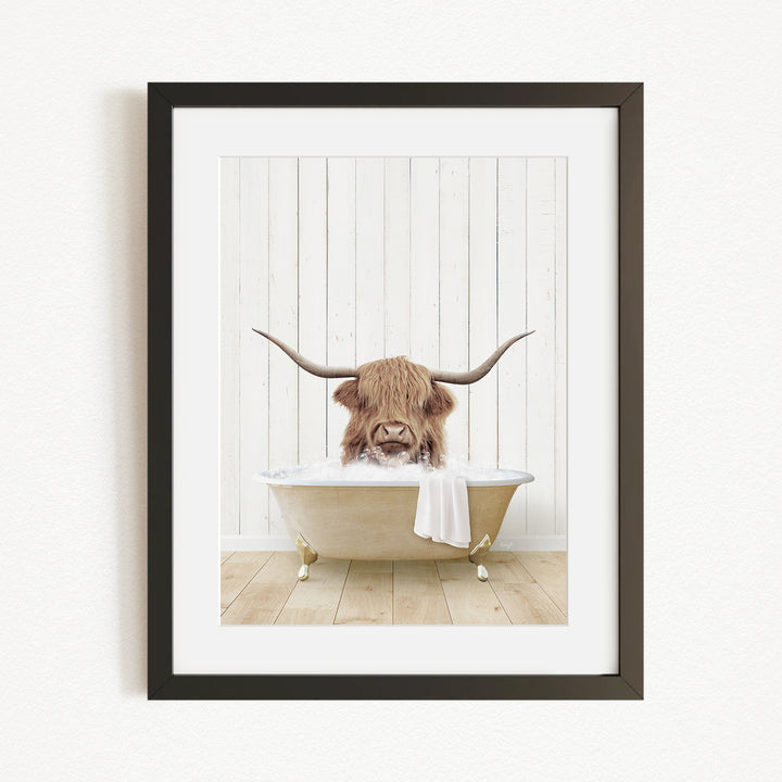 A framed image depicting a Highland cow with long horns sitting in a bathtub filled with water.