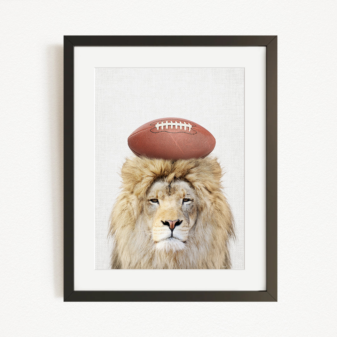 A framed image of a lion with a football on its head.