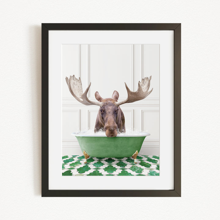 A moose with large antlers is sitting in a green bathtub, surrounded by a patterned green and white rug.