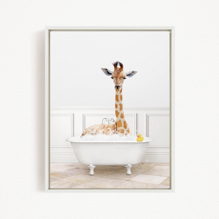 A giraffe sitting in a white bathtub filled with bubbles, with a yellow rubber duck floating in the water.
