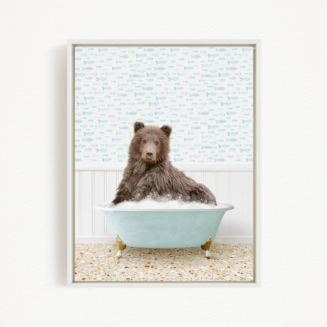 A brown bear sitting in a light blue bathtub filled with bubbles, surrounded by a pattern of fish on the wall behind it.