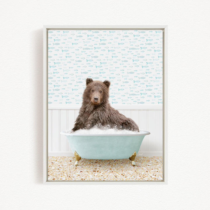 A brown bear sitting in a light blue bathtub filled with bubbles, surrounded by a pattern of fish on the wall behind it.