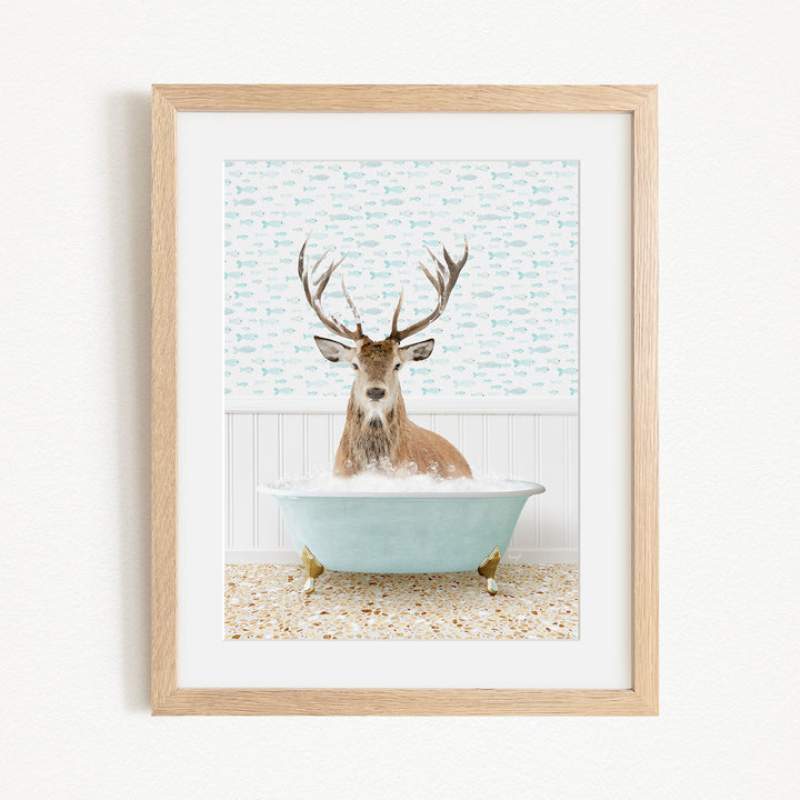 A deer with antlers is sitting in a light blue bathtub, surrounded by a patterned tile floor and a white wall.