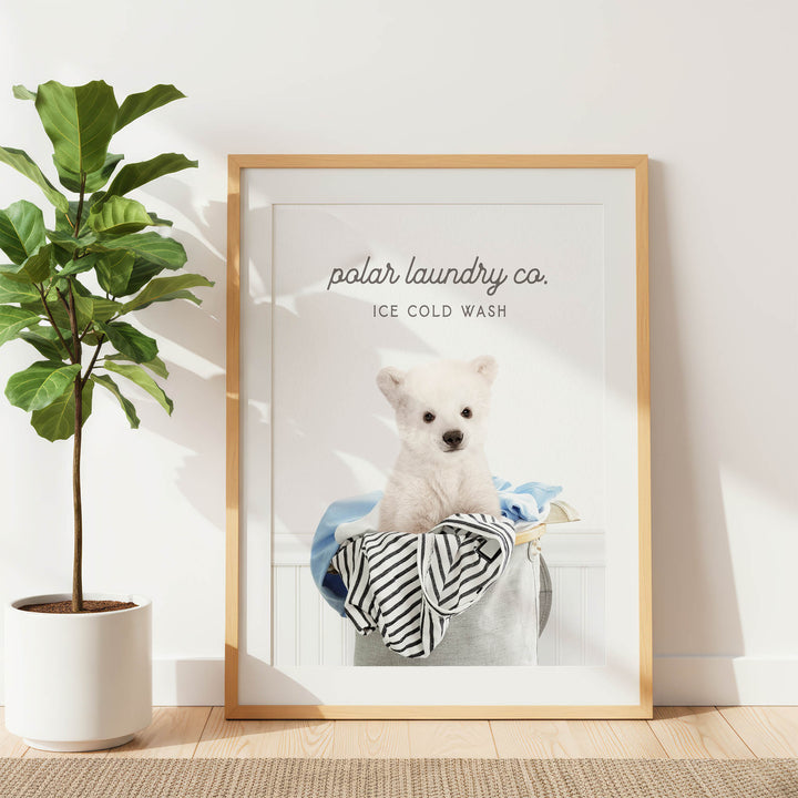 A framed poster featuring a white dog sitting in a laundry basket, with the text "ice cold wash" and "polar laundry co."