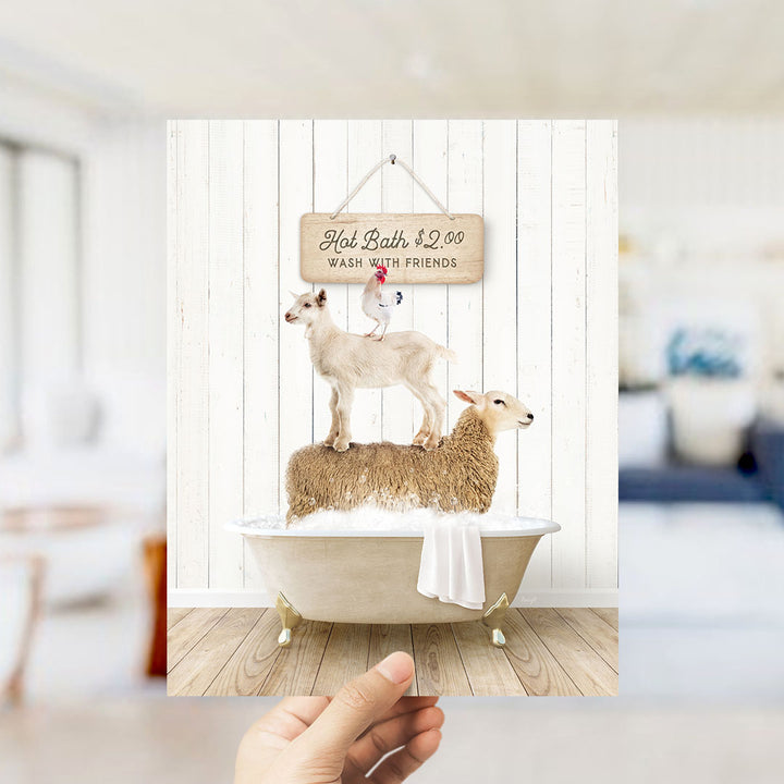 A hand holding a framed image of a white bathtub with two sheep standing on it, and a sign above the bathtub that says "Hot Bath $2.00 WASH WITH FRIENDS".
