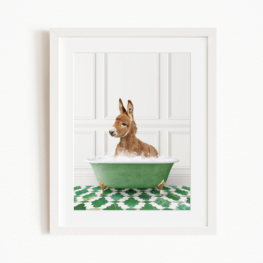 A donkey is sitting in a green bathtub filled with bubbles, surrounded by a green and white patterned rug.