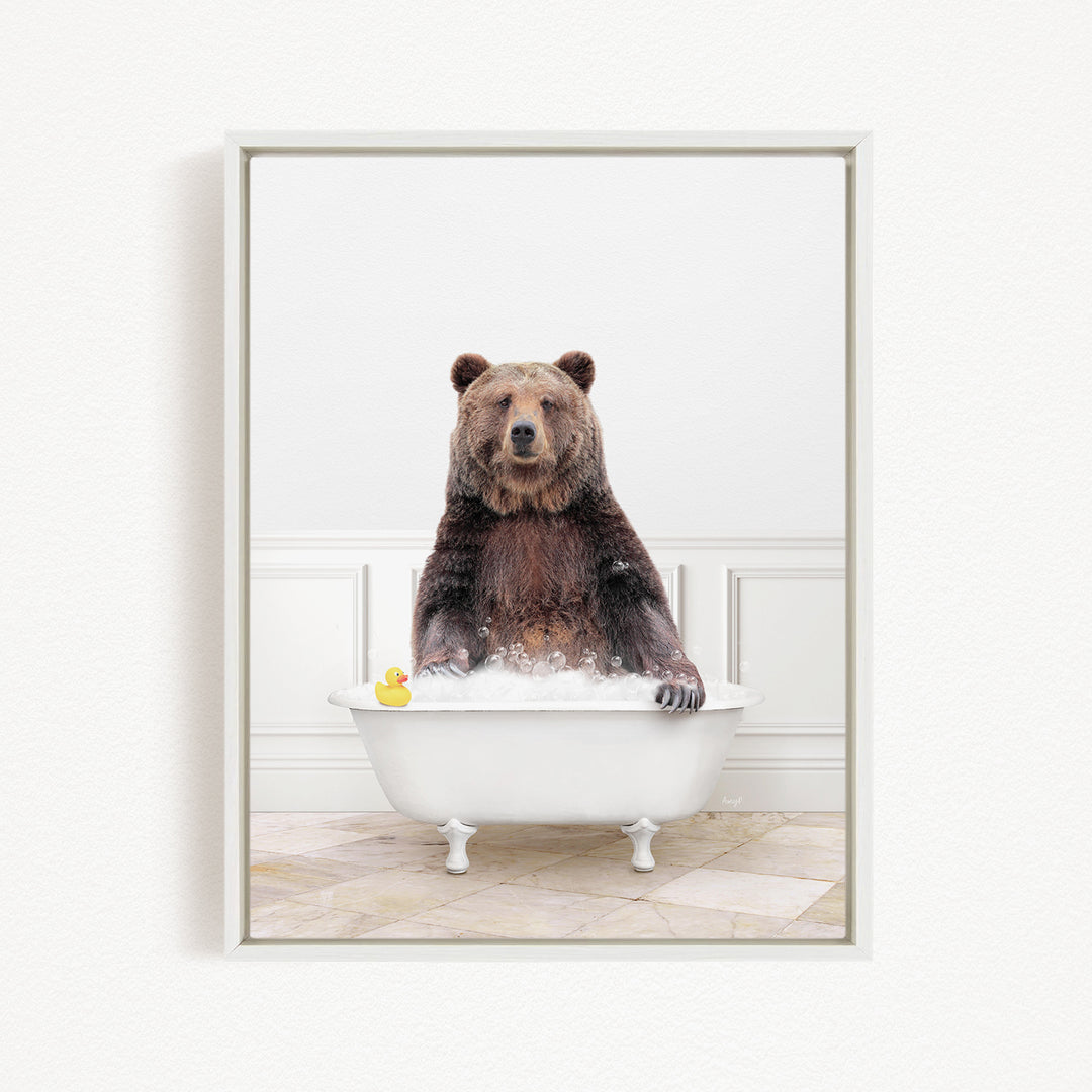 A brown bear sitting in a white bathtub, with a yellow rubber duck floating in the water.