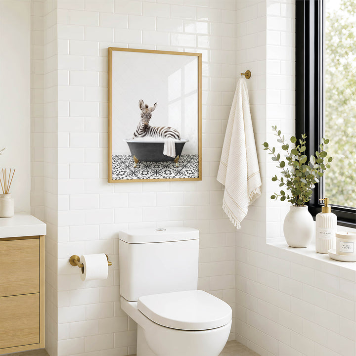 A bathroom with a white toilet, a framed picture of a zebra in a bathtub, and a window with greenery on the sill.