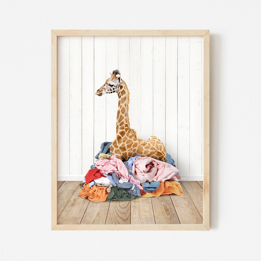 a giraffe sitting on top of a pile of clothes