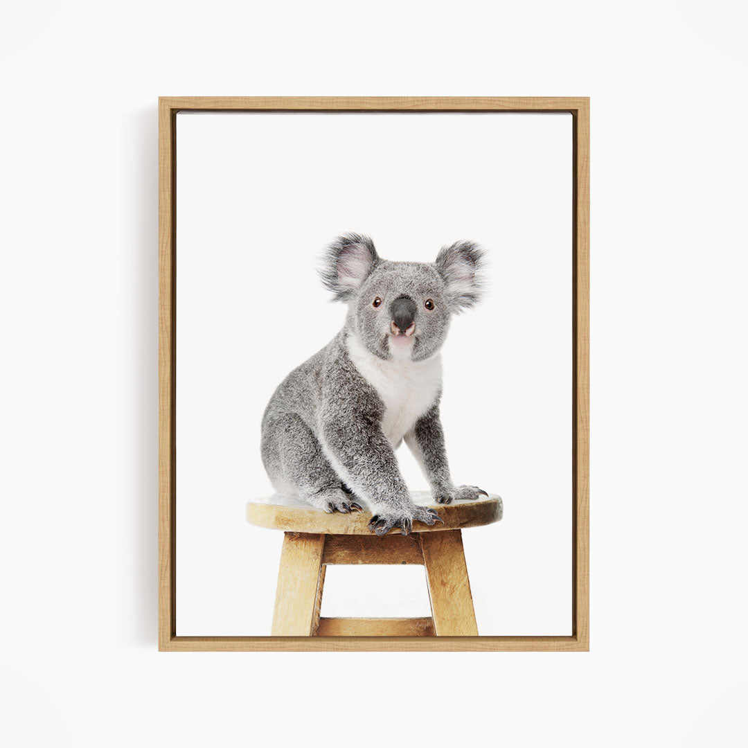 A koala sitting on a wooden stool.