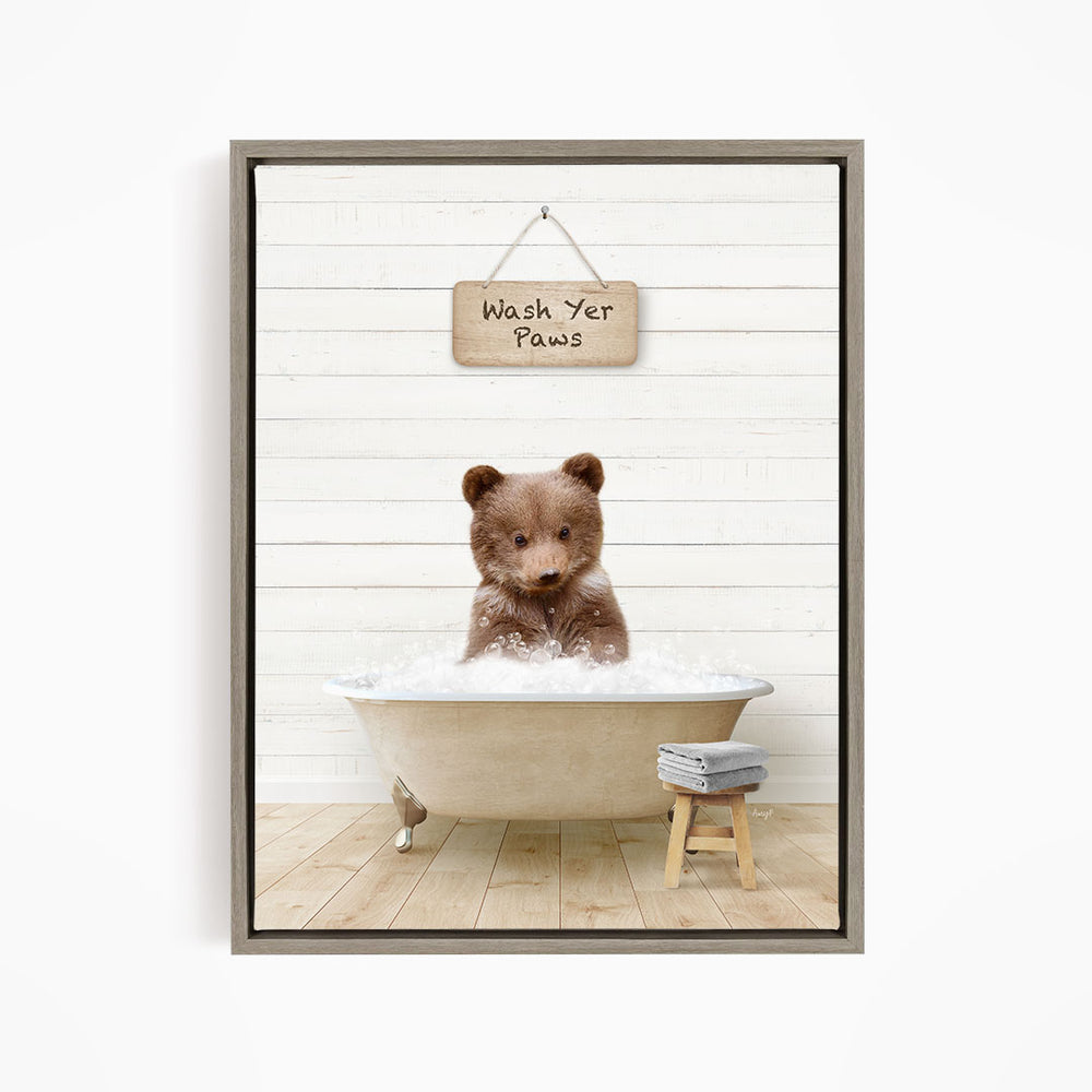 A cute brown bear sitting in a bathtub filled with water, with a sign above that says "Wash Your Paws".