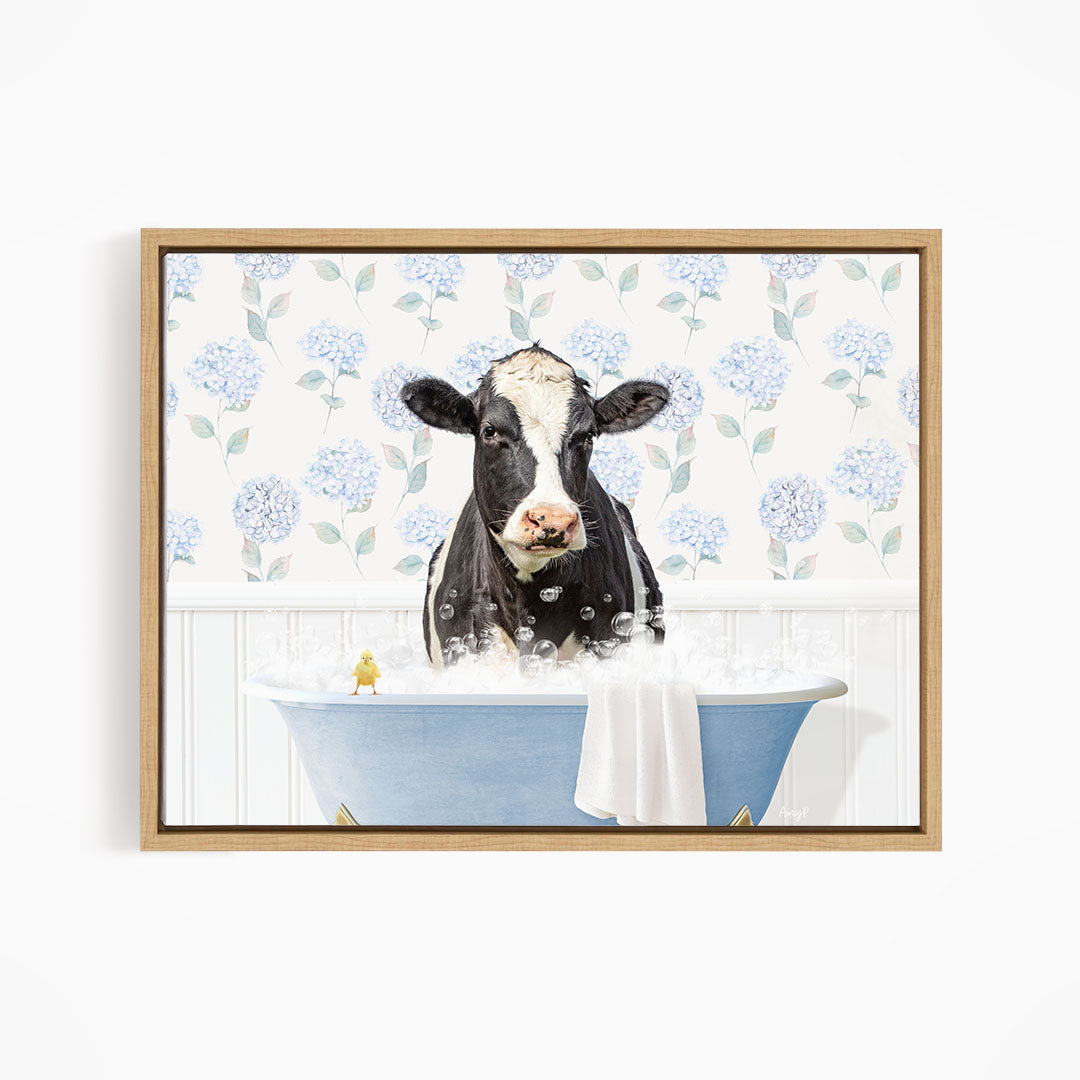 A black and white cow is sitting in a blue bathtub filled with bubbles, with a yellow bird perched on the edge of the tub.