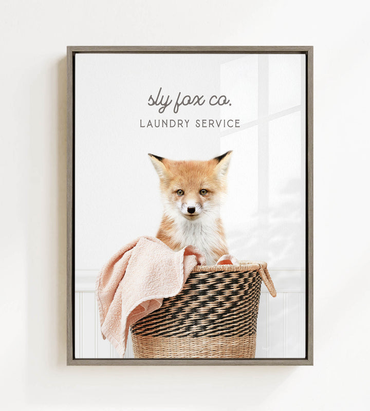 A young fox sits in a woven laundry basket, with a towel draped over its back.