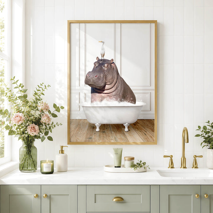 A framed image of a hippopotamus sitting in a bathtub, surrounded by flowers and a bird, is displayed on a white wall above a bathroom sink.