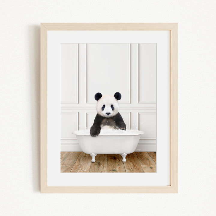 A panda bear sitting in a white bathtub, surrounded by a wooden floor and white walls.