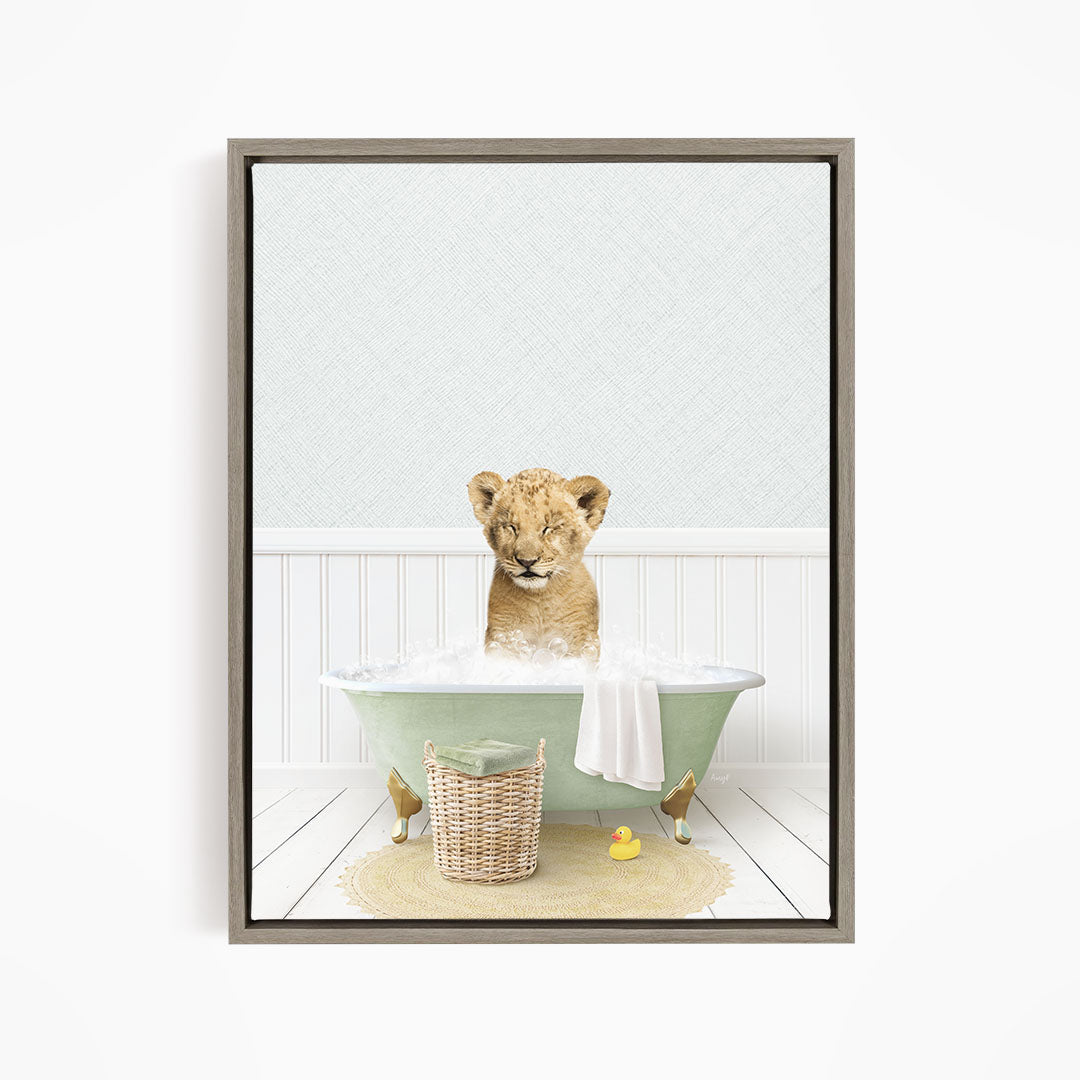 A young lion cub sitting in a green bathtub filled with water, surrounded by a basket of toys and a yellow rubber duck.