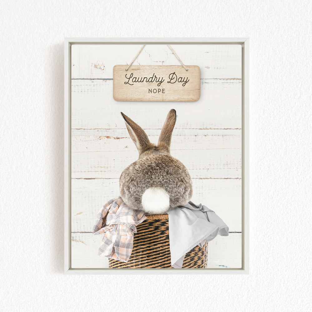 A wooden sign with the text "Laundry Day Hope" hangs above a basket containing a gray blanket and a plaid cloth.