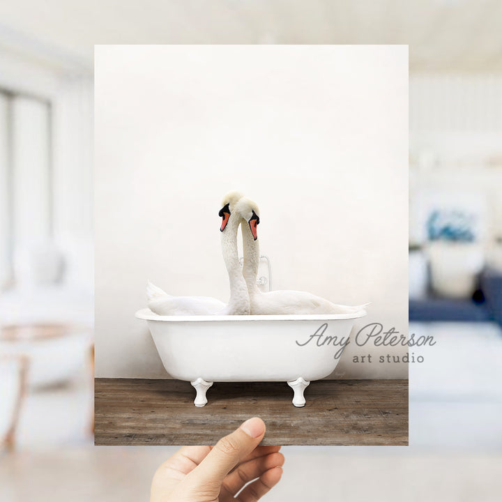 a person holding up a picture of two swans in a bathtub