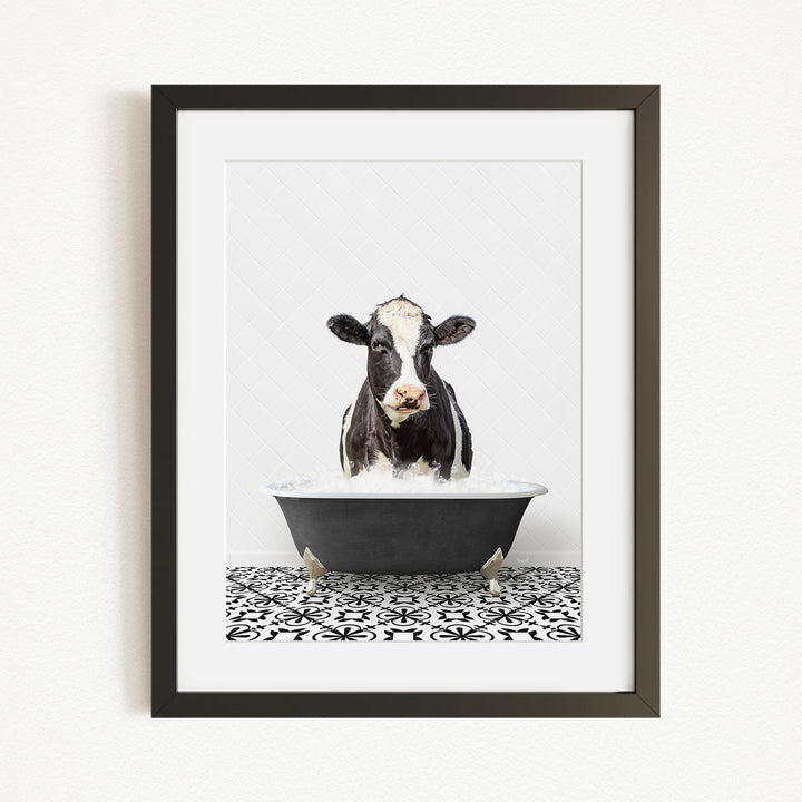 A black and white cow is sitting in a black bathtub filled with water, creating a whimsical and humorous scene.