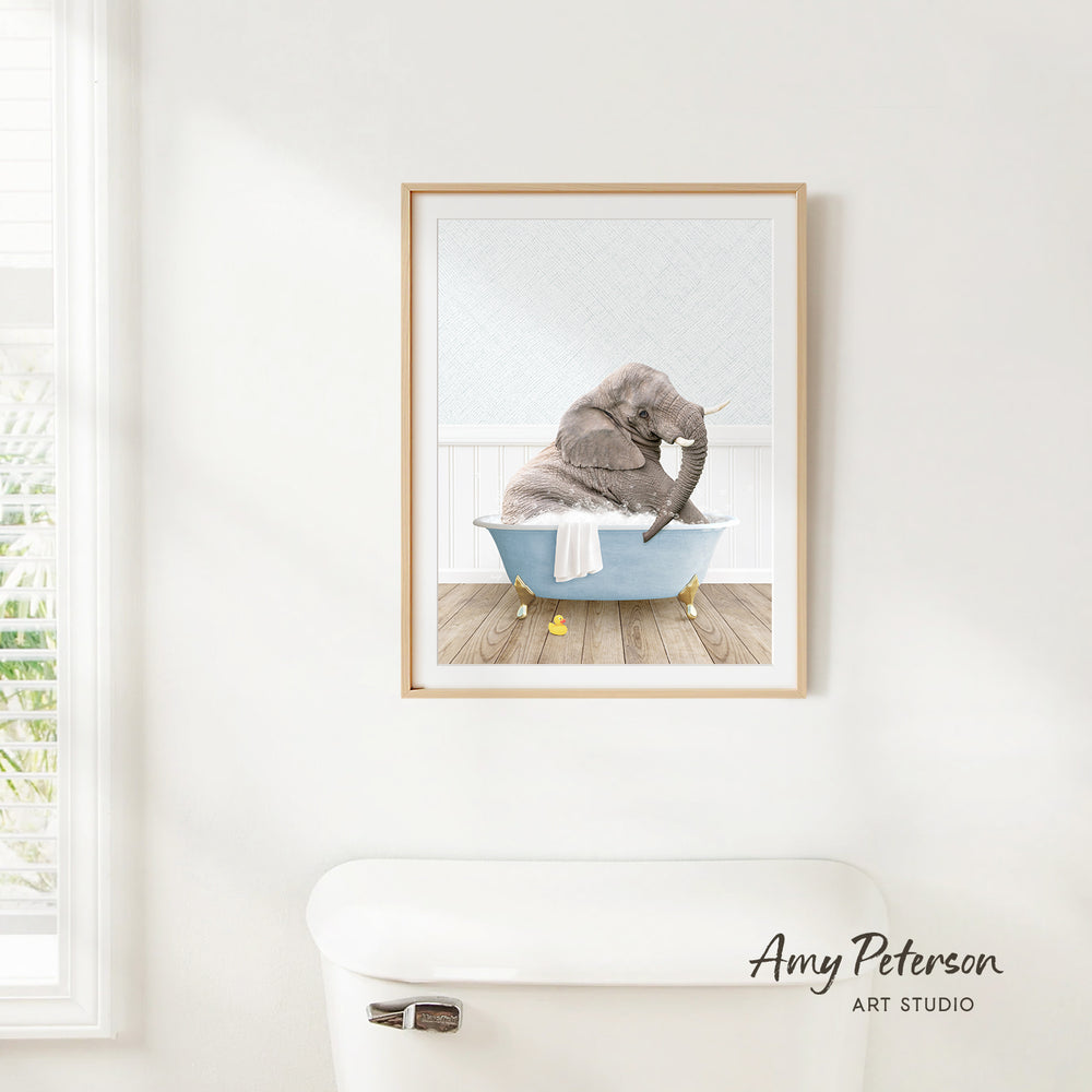 A framed image of an elephant sitting in a bathtub, with a towel draped over its body.