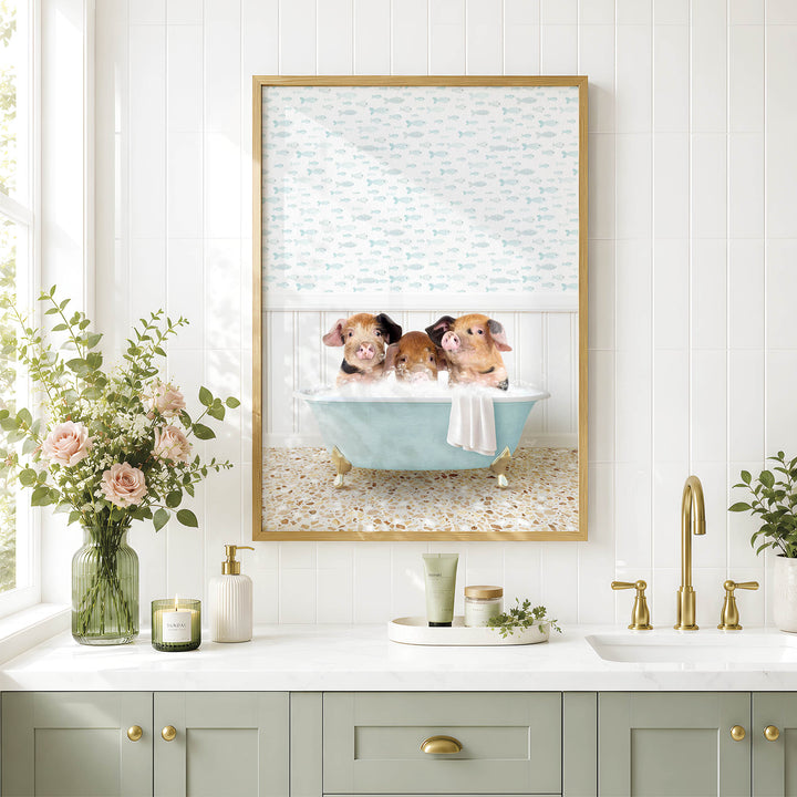 A framed image of three adorable pigs sitting in a bathtub, surrounded by flowers and greenery, is displayed on a white tiled wall above a bathroom sink.