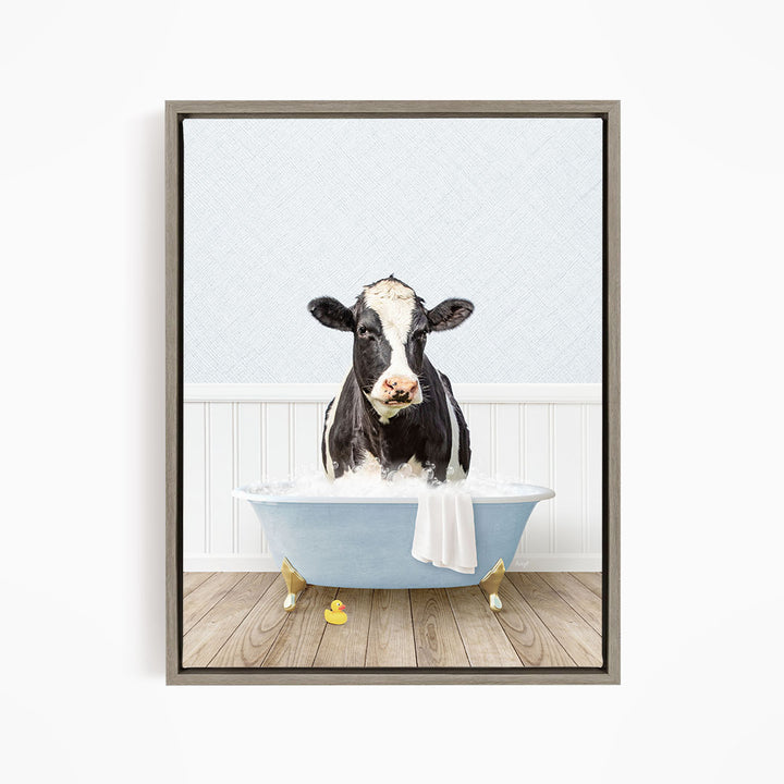 A black and white cow is standing in a blue bathtub filled with water, with a towel hanging on the side of the tub.