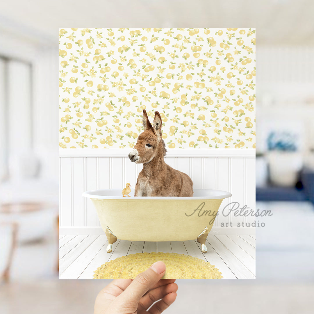 a hand holding up a photo of a donkey in a bathtub