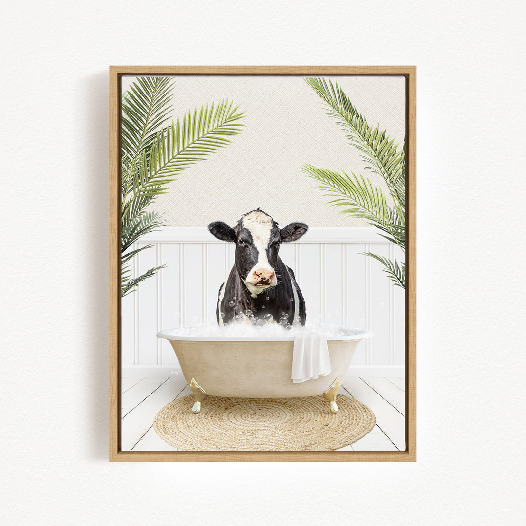A black and white cow is sitting in a white bathtub filled with water, surrounded by green palm leaves.